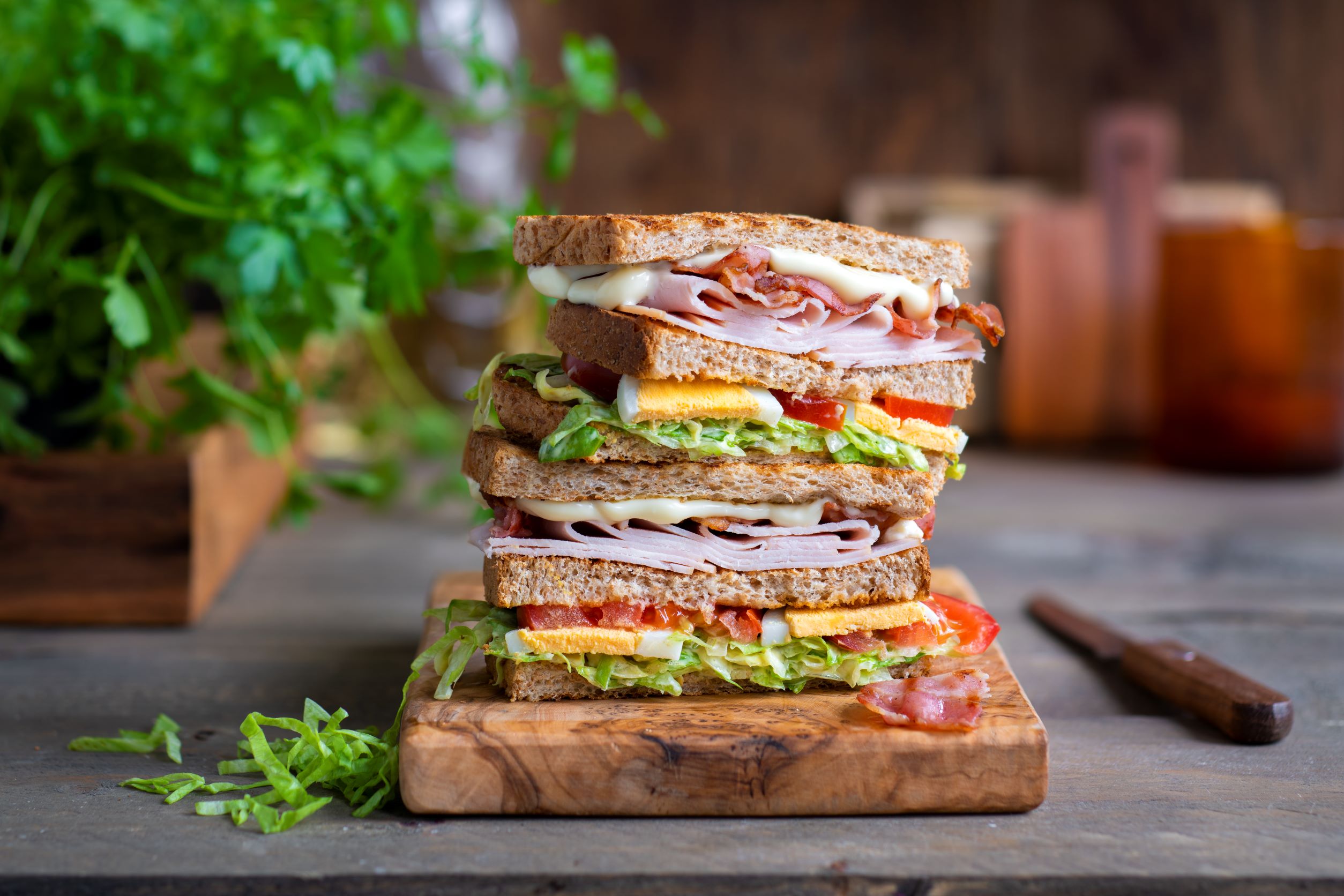 Club-Sandwich belegt mit Schinken, Ei, Salat, Tomate, Mayo und Senf