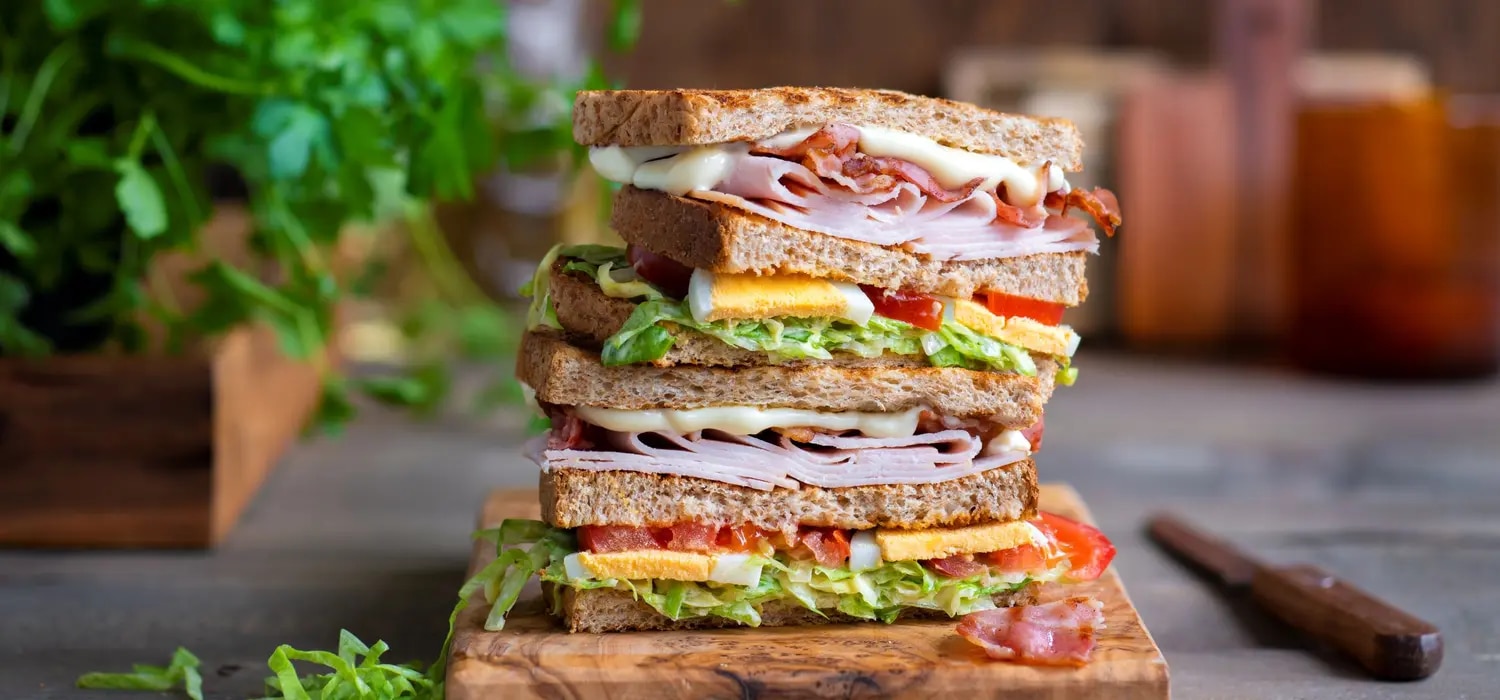 Club-Sandwich belegt mit Schinken, Ei, Salat, Tomate, Mayo und Senf