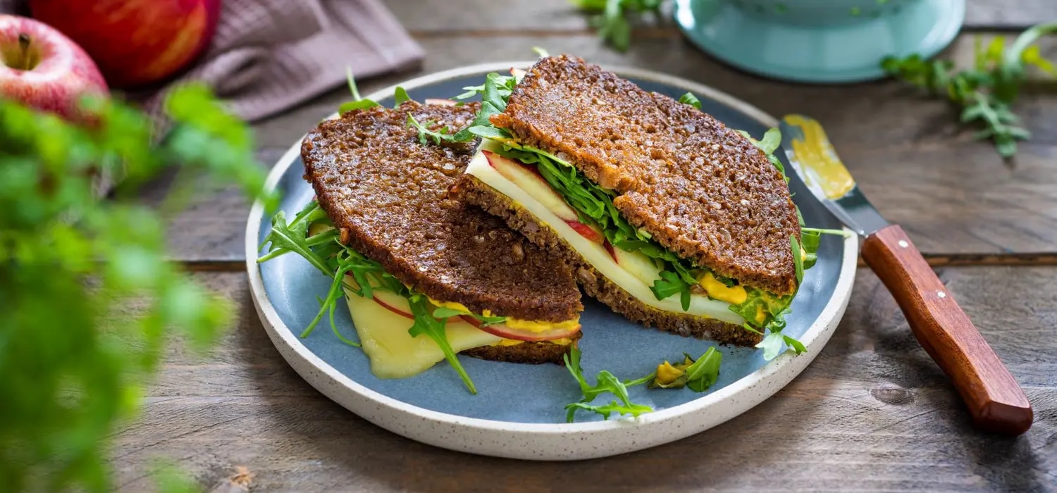 Schwarzbrot belegt mit Käse, Apfel, Rucola und Senf